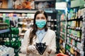 Stressed woman with mask shopping in grocery store with an empty wallet.Bankruptcy/recession.Covid-19 quarantine lockdown impact. Royalty Free Stock Photo