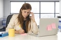 Stressed woman working with laptop computer on desk talking on mobile phone taking notes Royalty Free Stock Photo