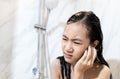 Stressed worried asian child girl had tinnitus water in her ear canal while washing her hair,female cleaning her ear while taking