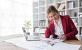 Stressed young Asian businesswoman focuses on rechecking the business financial investment plan's report at her desk Royalty Free Stock Photo