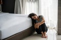 Stressed young Asian woman suffering on depression and sitting alone in bed room. Sad, unhappy, disappointed, domestic abuse or Royalty Free Stock Photo