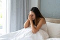 Stressed young Asian woman suffering on depression and sitting alone in bedroom at home. sad, unhappy, disappointed concept