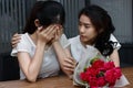 Stressed young Asian woman supporting depressed crying female friend in living room. Break up or best relationship concept. Royalty Free Stock Photo