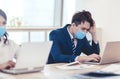 Stressed young business man wear face mask and working on laptop in office