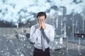 Stressed young businessman covering face with creative image of cloud data icons on blurry background. Cloud computing, big data, Royalty Free Stock Photo