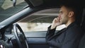 Stressed businessman swearing and talking phone while sitting inside car outdoors Royalty Free Stock Photo