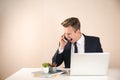 Stressed young businessman talking on mobile phone at table Royalty Free Stock Photo