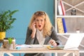 Stressed young businesswoman talking on phone in office Royalty Free Stock Photo