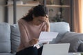 Stressed young caucasian woman reading paper with bad news. Royalty Free Stock Photo