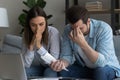 Stressed young couple calculating expenses feel upset