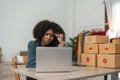 Stressed young entrepreneur African American woman and courier parcel box at home office. Small business owner, online Royalty Free Stock Photo