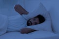 Stressed young indian man covering head with pillow while lying in bed Royalty Free Stock Photo