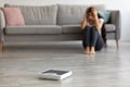 Stressed young Indian woman sitting on floor, grabbing her head in terror, looking at empty scales, feeling overweight Royalty Free Stock Photo