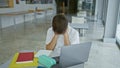 Stressed young man studying with laptop and books at university library table