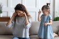Stressed young mother covering ears, annoyed by bad daughters behavior.