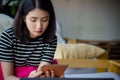 Stressed young professional business woman using tablet computer in Coffee shop. Asian female sitting on couch using tablet ipad Royalty Free Stock Photo