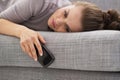 Stressed young woman with cell phone laying on couch