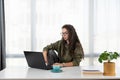 Stressed young woman holding head in hands and feeling demotivated while sitting at her home office and working remotely on laptop Royalty Free Stock Photo