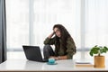 Stressed young woman holding head in hands and feeling demotivated while sitting at her home office and working remotely on laptop Royalty Free Stock Photo