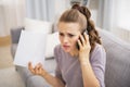 Stressed young woman holding letter and talking cell phone Royalty Free Stock Photo