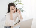 Stressed young woman working on  laptop and talking on the phone in the home office Royalty Free Stock Photo