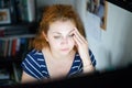 Stressed young woman working late on a computer