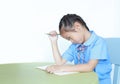 Stressful Asian little schoolgirl studying and tired with doing her homework on desk over white background. Kid girl use pencil Royalty Free Stock Photo