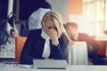 Feeling tired and stressed. Frustrated adult woman keeping eyes closed from fatigue while sitting in office.