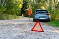 Stressful young woman driver hitchhikes and stops cars, asks for help as have problem with brocken car, uses red triangle sign Royalty Free Stock Photo