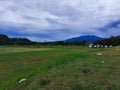 a stretch of green field with very cloudy weather