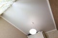 Stretch white matte ceiling close-up with a chandelier in the interior of a rectangular room