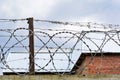 Stretched barbed wire against the sky and the roof Royalty Free Stock Photo