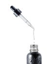 Stretched drop dripping from a cosmetic pipette isolated on a white background. Black bottle with cosmetic oil close up Royalty Free Stock Photo