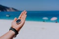 Stretched hand palm with black metal compass against sandy beach and blue sea. Follow your way, goal, wish concept