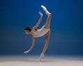 Slim tender young beautiful girl, female ballet dancer dancing isolated over blue background. Royalty Free Stock Photo