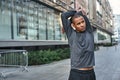 Stretching before great morning workout. Close up portrait of athletic african man standing outside and stretching his