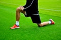 Stretching on green grass. Exercise photo, edit space. Professional athlete, football player