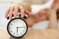 Stretching hand of sleepy young woman trying kill alarm clock Royalty Free Stock Photo