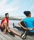 Stretching, legs and couple in exercise at beach to start fitness, training or outdoor on deck. Workout, preparation and