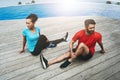 Stretching, legs and couple in exercise on deck to start fitness, training or outdoor with pool. Runner, workout and Royalty Free Stock Photo