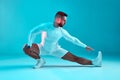 Stretching workout. Athletic flexible young man fitness trainer stretches leg muscles on blue background. Long exposure