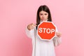 Strict bossy woman pointing to camera and holding Stop road traffic sign as symbol of prohibition. Royalty Free Stock Photo