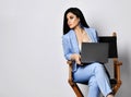 Strict business woman in blue formal wear sits with laptop on armchair looks sternly at something on the side of her Royalty Free Stock Photo