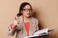 Strict female teacher with glasses, points her index finger at camera, warning you about the importance of reading books