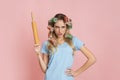 Strict housewife with curlers holds rolling pin