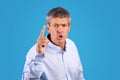 strict mature man shaking finger looking at camera, blue background