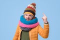 Strict mature man in winter scarf and hat showing index fingers up