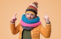 Strict mature man in winter scarf and hat showing index fingers up