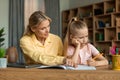 Strict mother studying with little schoolgirl daughter, scolding lecture for bad marks, girl unmotivated to do homework