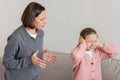 Strict sad millennial caucasian woman scolding teenage daughter, covering ears with hands, freaking out Royalty Free Stock Photo